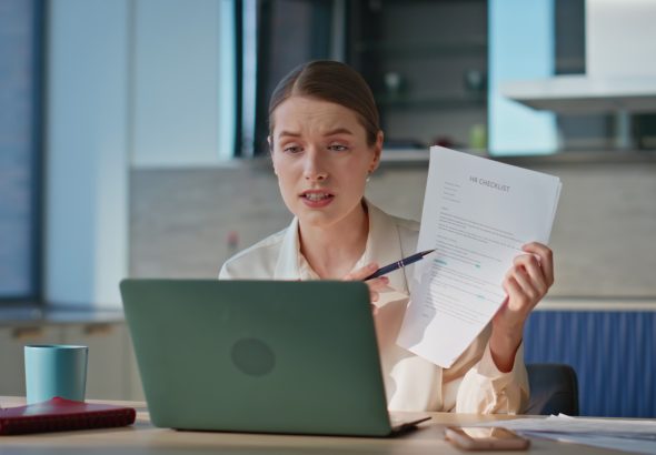 Online tutor showing papes to laptop webcam sitting modern kitchen closeup.